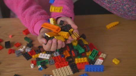 Many Lego pieces falling into the hands of a girl