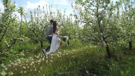 Married couple running through trees.