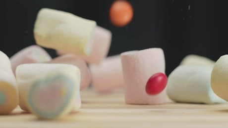 Marshmallows and candies falling down in slow motion.