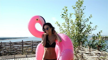 Millennial woman in bikini with flamingo float.