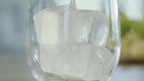 Mineral water pouring over ice in a glass.