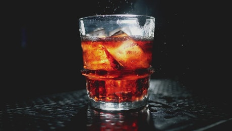 Mixing cola with ice cubes in a glass.