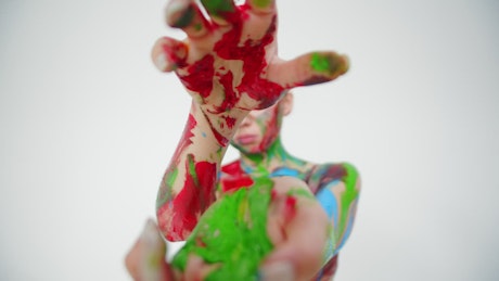 Model covered in body paint moving her hands close at the camera.