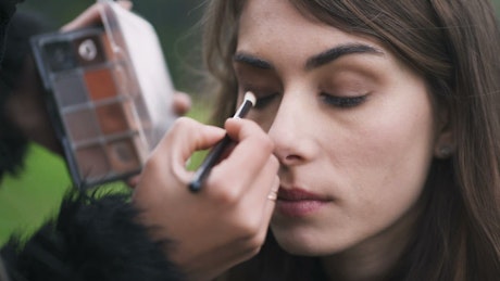 Model having eyeshadow applied by a make up artist.