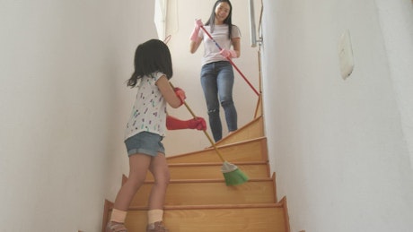Mom and daughter sweeping the stairs at home.