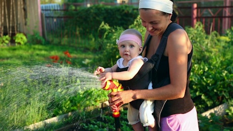 Mom watering the garden with her baby.