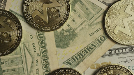 Monero cryptocurrency coins over dollar bills.