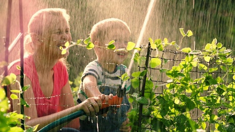 Mother and child spraying a hose