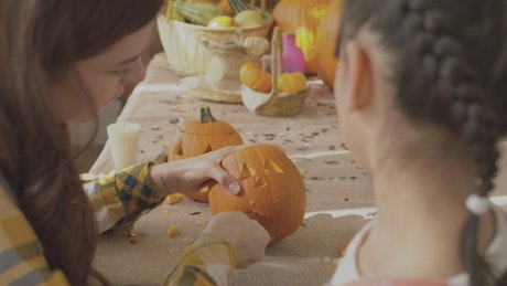Mother and daughter making pumpkins for halloween.