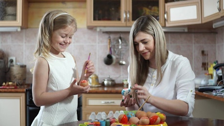 Mother and daughter painting egg shells for Easter.
