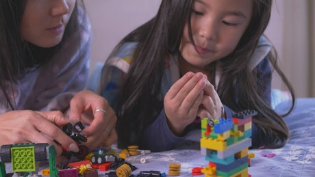 Mother and daughter playing together with legos.