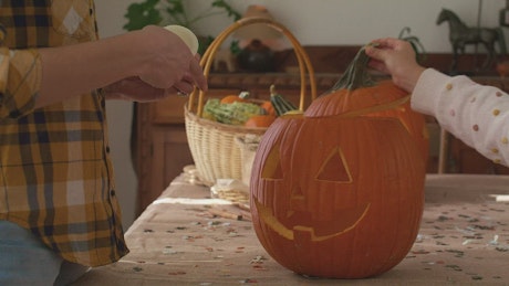 Mother and daughter putting a candle inside a halloween pumpkin.