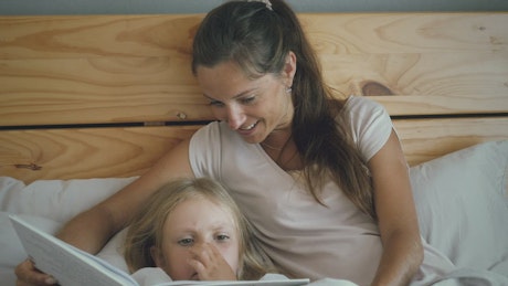 Mother and daughter reading in bed.