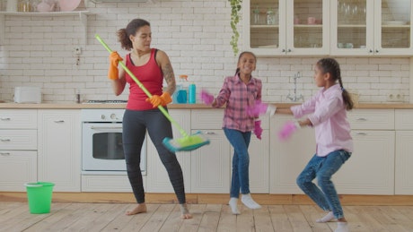 Mother and daughters in a kitchen dancing.