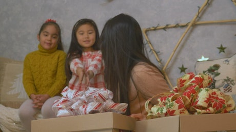 Mother and daughters opening presents on christmas day.