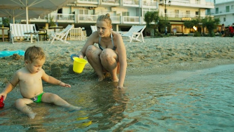 Mother and son playing in wet sand.