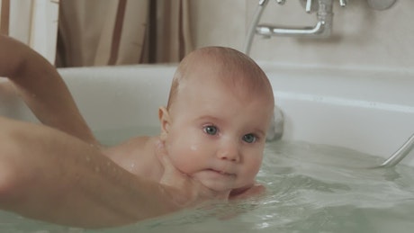 Mother bathing her baby in the tub.