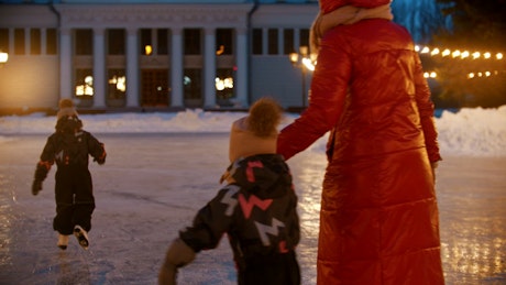 Mother doing ice skating with her small children.