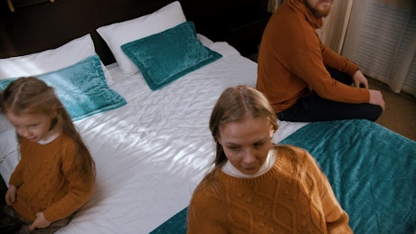 Mother, father and daughter lying on a bed.