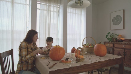 Mother making pumpkins for halloween with her daughter.