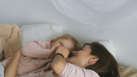 Mother playing with daughter on the bed.