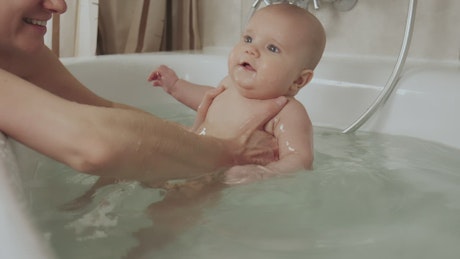 Mother playing with her baby in a tub of water.
