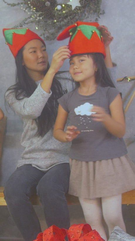Mother trying on Christmas hats with her little daughter.