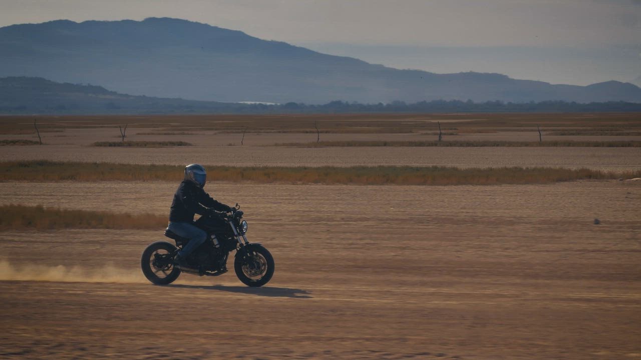 Pengendara sepeda motor melintasi LIVE DRAW TOTO WUHAN di gurun pasir yang dikelilingi pegunungan