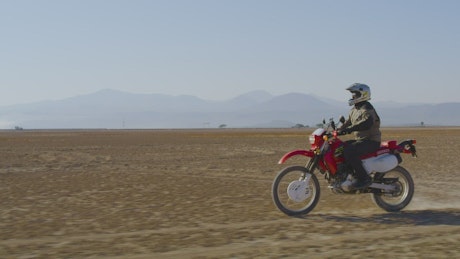 Motorcyclist doing a wheelie in the desert.