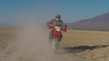 Motorcyclist on a red motorcycle in the desert.
