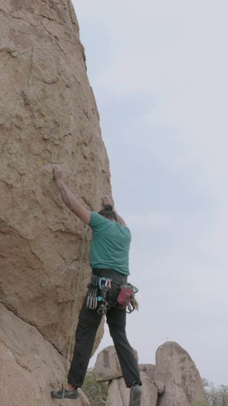 Mountain climber climbing a vertical rock face.