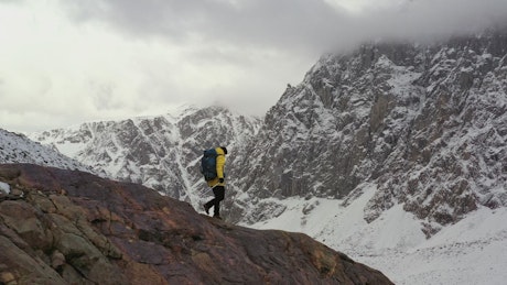 Mountaineer walking on a cliff in a winter mountain range