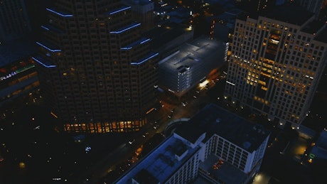 Movement in a city at night in an aerial shot.