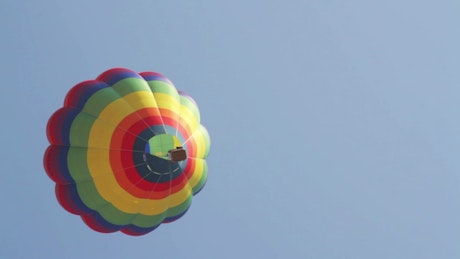 Multicolored hot air balloon is seen from below.