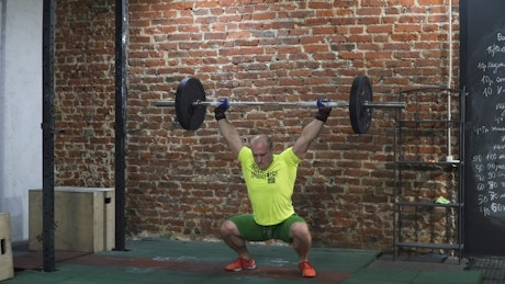 Muscled man lifting a barbell over his head.