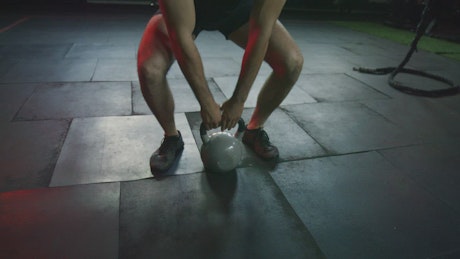 Muscular man exercising with a kettlebell.