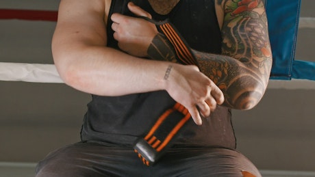 Muscular man putting an elastic bandage on his wrist.