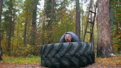 Muscular man training with a tractor tire.