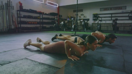 Muscular woman and man stretching in a gym.