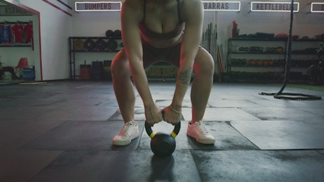Muscular woman exercising with a kettlebell.