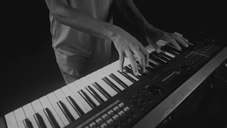 Musician playing on a keyboard, black and white.
