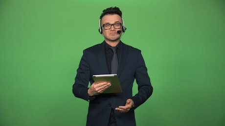 Newscaster with tablet and headset speaking.