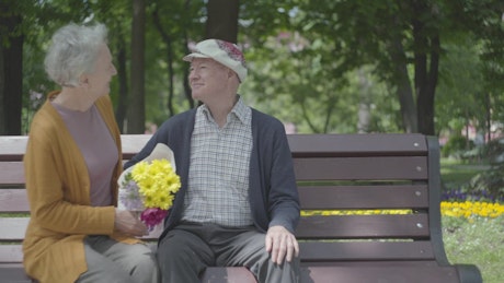 Old couple sitting on a bench in a park.