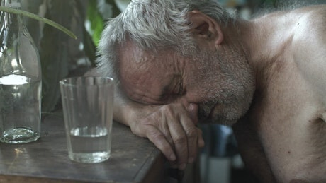 Old shirtless drunk man sleeping on a table
