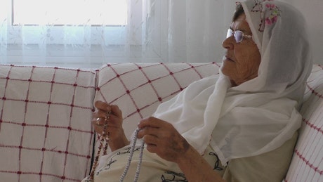 Old woman praying at home.
