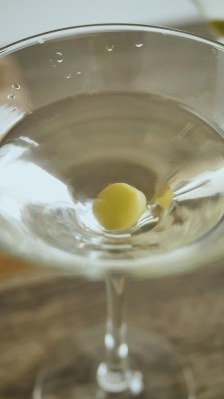 Olive falling into a martini glass.