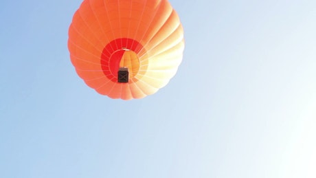 Orange hot air balloon flying.