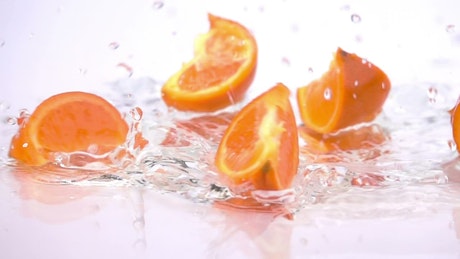 Orange slices falling into water.