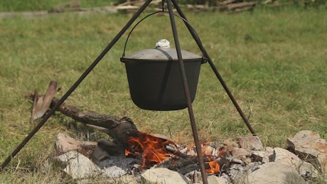 Outdoor cooking in a campfire cauldron.