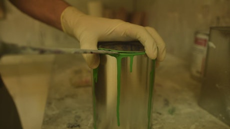 Painter opening a can of green paint